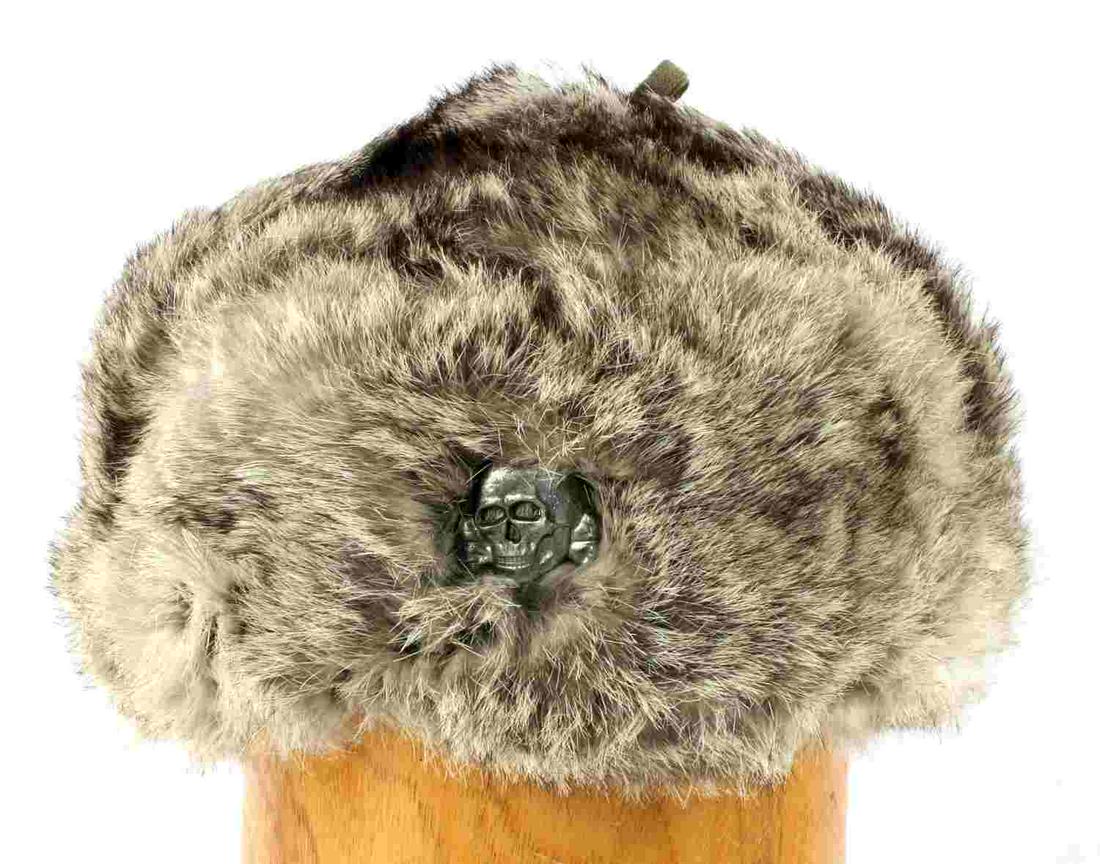 WWII GERMAN THIRD REICH WAFFEN SS RUSSIAN FUR CAP: WWII German Third Reich Waffen SS Russian Front Fur Cap. The body is a light grey and black rabbit fur. There is a metal Waffen SS skull mounted onto the front. The interior has a green quilted cotton