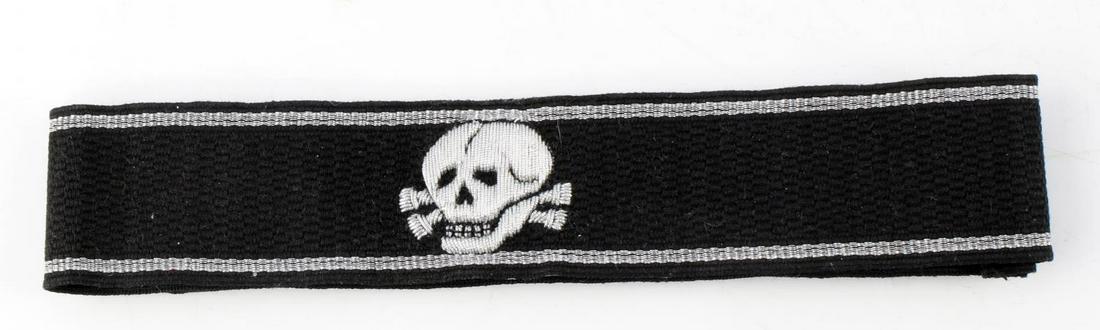 WWII GERMAN SS TOTENKOPF OFFICERS CUFF TITLE: Measures 18 1/2” wide by 1 1/4” tall. The front shows a skull and cross bones in the center. The ends are sewn. There is a paper â€˜SS RZMâ€™ tag on the reverse side. Machine embr