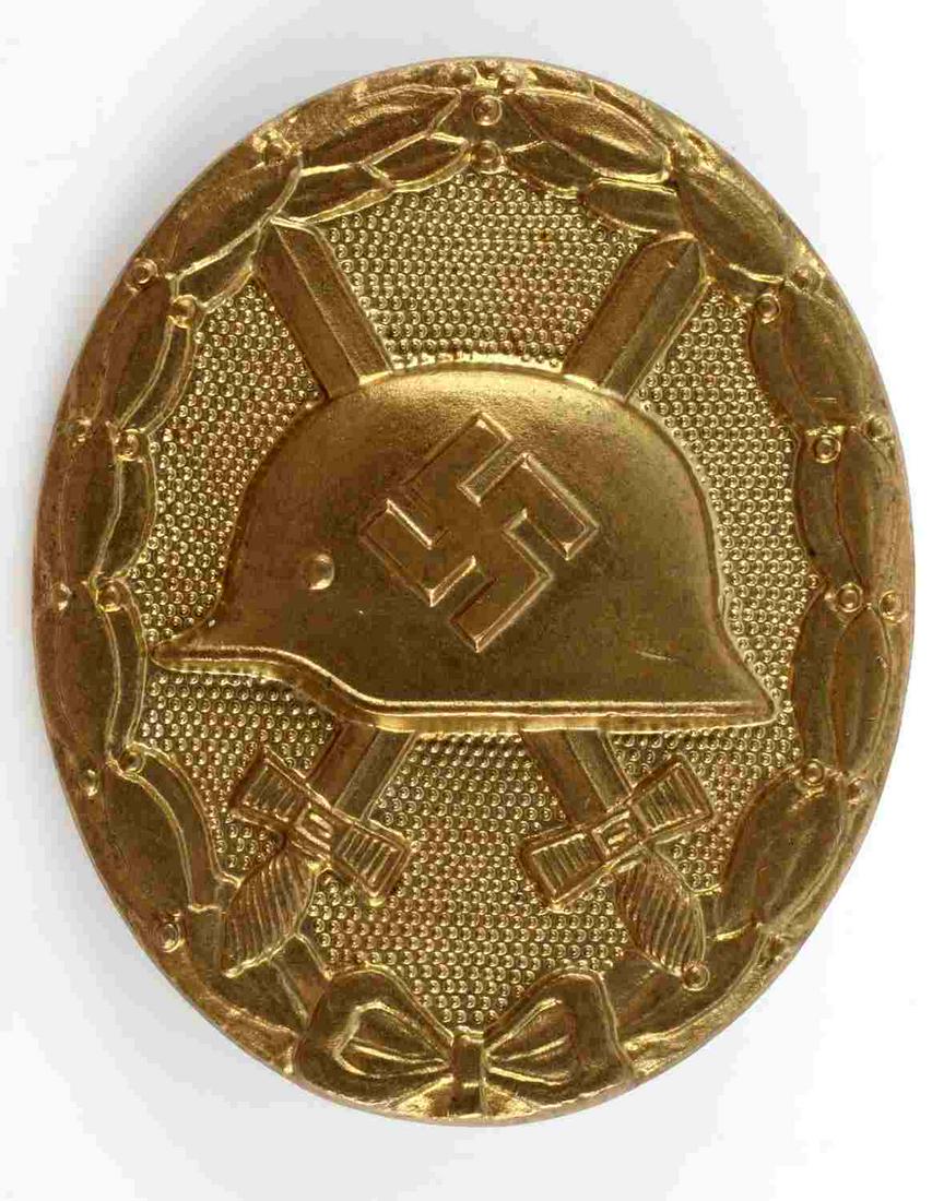 WWII GERMAN THIRD REICH NSDAP GOLD WOUND BADGE: WWII German Third Reich GOLD Wound Badge. Measures 1 7/16 X 1 3/4 inches. The front shows a German helmet in the center with a pair of crossed swords in the back ground. All three are surrounded by an