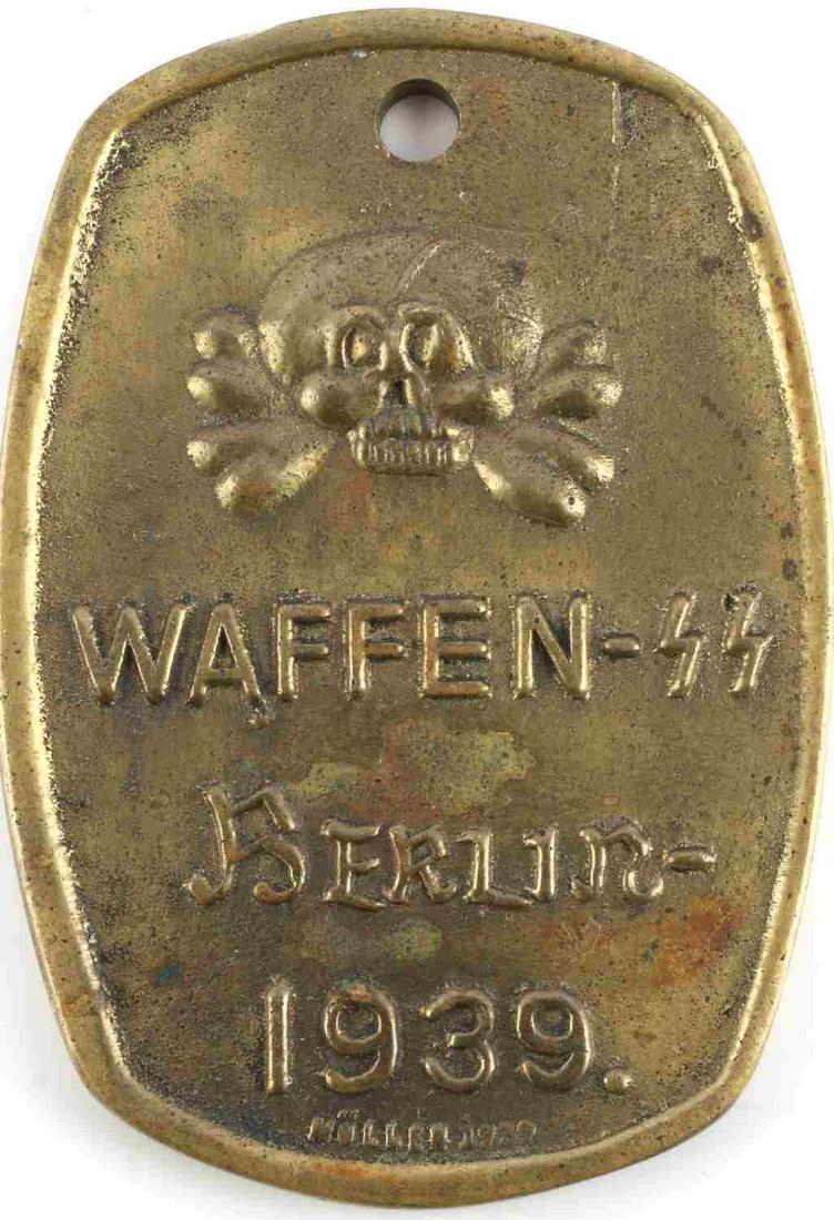 WWII GERMAN THIRD REICH WAFFEN SS BRASS ID BADGE: German WWII Waffen WW Berlin 1936 ID Disc. Measures 1 15/16” wide by 2 3/4" inches tall. The front shows a skull and cross bones. It reads ‘Waffen SS Berlin – 1936’. The reverse side is marked