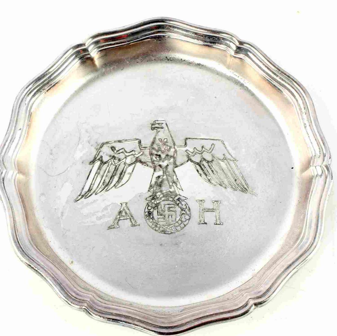 WWII GERMAN WELLNER ALPACCA SILVER PLATE COASTER: Small 4 5/8 inch scalloped edge coaster with eagle and Hitler's initials at center. Marked 'Wellner alpacca schwerversilbert' marked to reverse. Very good condition.