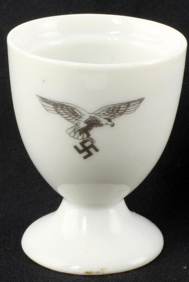 WWII GERMAN LUFTWAFFE PORCELAIN EGG CUP: WWII German Luftwaffe porcelain egg cup. Front features the Luftwaffe eagle in black ink. Bauscher Weiden 1940 maker mark to underside. 2 1/2 inches tall. Loss to the base. Unauthenticated, sold as is