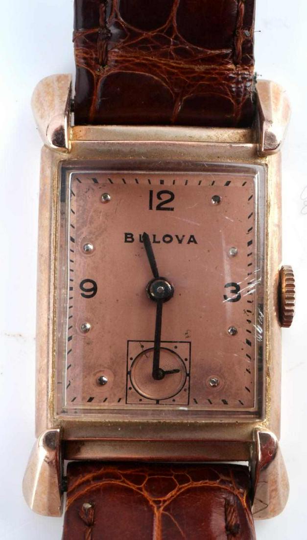 14KT ROSE GOLD BULOVA 1940'S MECHANICAL WATCH: Classic 1940's Bulova watch with rectangular case, copper dial and lightly used leather strap. Case marked 14kt Bulova 6450097. Watch movement starts and holds. Crystal is intact but needs buffing.