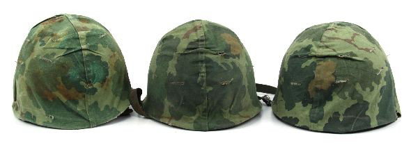 THREE VIETNAM ERA M-1 HELMETS WITH LINERS: Grouping of (3) swivel bale M-1 helmets circa Vietnam to 1970's. All have liners and reversible Mitchell Camoflauge covers. Overall used but good condition.