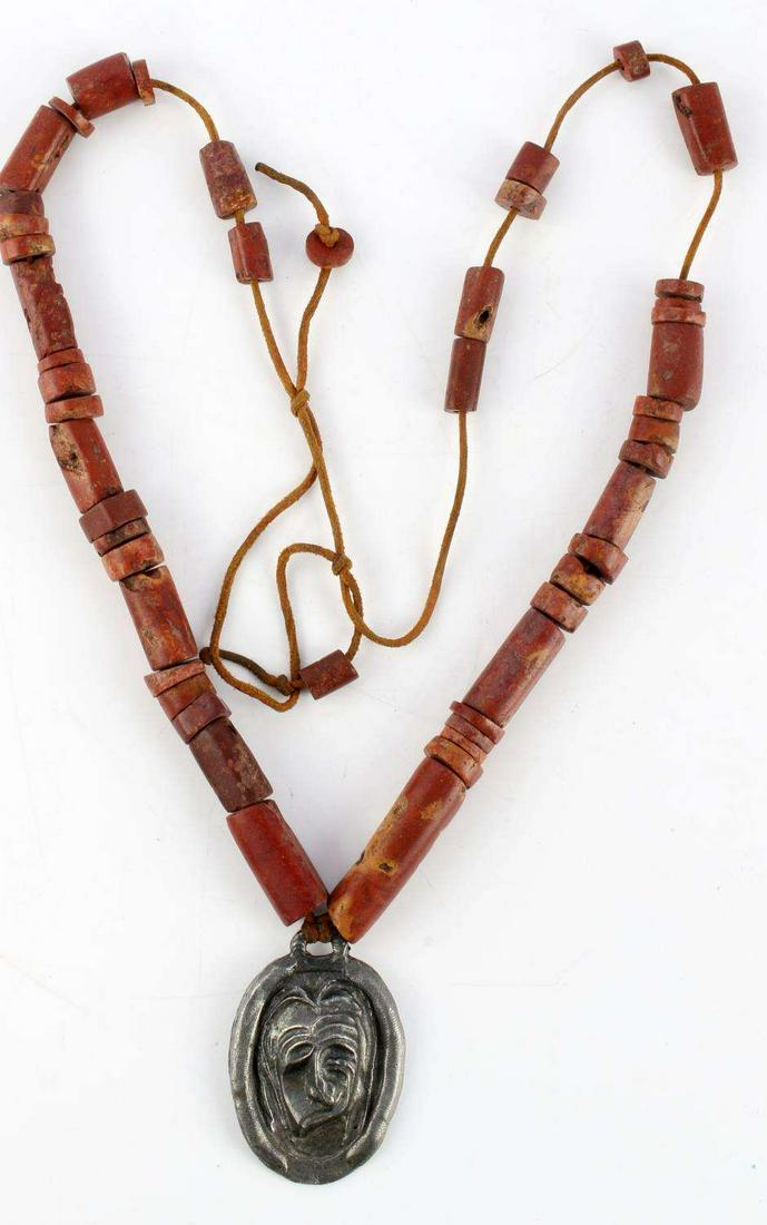 NATIVE IROQUOIS FALSE FACE PENDANT TRADE NECKLACE: Trade bead necklace with pieces ranging from 4 to 44 mm in size with leather cord, probably later restrung . Pewter false face medicine man pendant or possibly talisman. Pendant is 60mm in length. Num