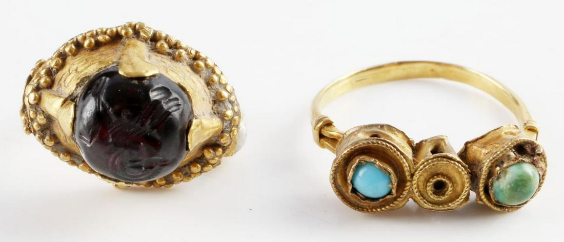 ANCIENT ROMAN INTAGLIO GOLD AND GEMSTONE RINGS: 2 Ancient Roman rings, metal detector finds, tested at high carat (over 18kt) with debitage in the recesses. One with a carnelian intaglio of an antelope. Each ring is missing a stone. Total weight 7.