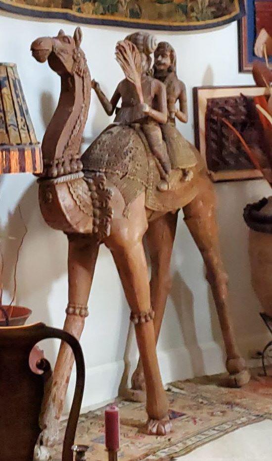 ANTIQUE WOOD HOLLYWOOD SCREEN USED CAMEL PROP: Giant one of a kind wooden carved antique possibly 18th century camel statue sculpture, possibly Middle Eastern, with man and woman riders. Purported to be a Hollywood "screen-used" prop or piece of s