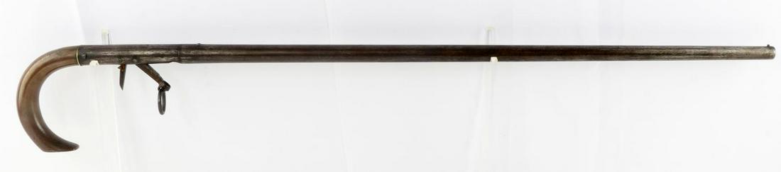 ANTIQUE WALKING CANE PERCUSSION GUN 11 MM BORE: Cap and ball cane gun, bore measures 11 mm across, dusty but clear bore, heavy brass handle, entire length is 31.5 inches with bead front sight, and flattened, notched rear sight. Unknown maker. Good 