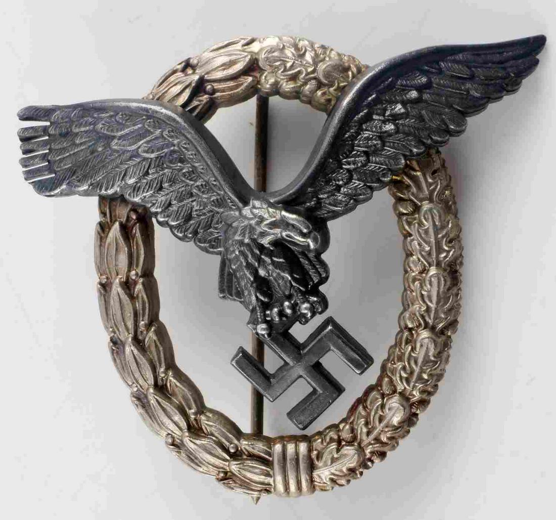 WWII GERMAN THIRD REICH LUFTWAFFE PILOT BADGE: WWII German Third Reich Luftwaffe Pilot Badge, measures approx. 2.5 X 2 inches. The front shows a flying eagle clutching a swastika in his talons in the center. Both are surrounded by an oval oak leaf