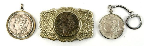MORGAN SILVER DOLLAR LOT IN BUCKLE & KEY CHAINS: A group of Morgan dollars in embedded in a nickel silver belt buckle dated 1921, a key chain Morgan 1888o, and a silver pendant Morgan 1880s.