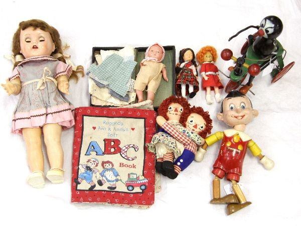 ANTIQUE DOLLS PINOCCHIO IDEAL DOLL RAGGEDY ANN: Grouping includes Walt Disney's Pinocchio wooden doll, Ideal Saucy Walker doll, Raggedy Ann and Andy plus their cloth book, wooden painted black toy on a tricycle, Annie doll, Scottish doll missing a