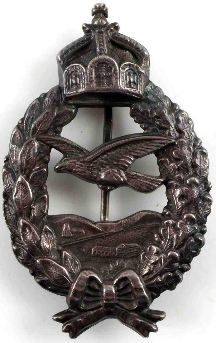 WWI IMPERIAL GERMAN COMMEMORATIVE PILOT BADGE: Features crown on top with oak and laurel leaf wreath surrounding eagle in flight. Reverse is a vertical pin and C catch marked with CE Junker, 800, and German silver hallmark crown and crescent. Meas