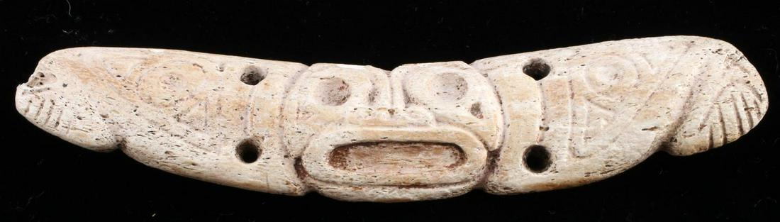 NATIVE AMERICAN TAINO BONE BAR FACE MEDALLION: Bone bar medallion with anthropic face. Bird head symbols are Incised on extensions. Interpretive hands appear at the ends of the extension suggesting the arms are spread. Manatee rib. Taino Culture C