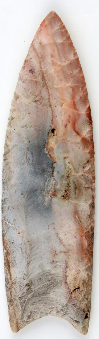PALEO NATIVE AMERICAN 5.5 INCH CLOVIS ARROWHEAD: Measures 5.5 inches. Major edge wear on both sides. Mineralized and nicely patinated. Fluting measures 2 1/4 inches. Smooth feel. Very good condition.