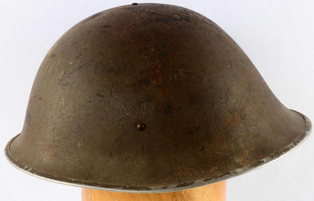 WWII BRITISH MARK IV BMB TURTLE SHELL HELMET: WWII British Mark IV "turtle shell" helmet. Green painted helmet with olive cloth strap and black leather liner. Partially visible makers mark can be identified as "BMB" for Briggs Motor Bodies Ltd of