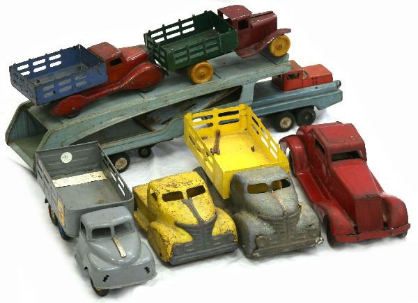 LOT 7 PRESSED METAL VINTAGE TOY CARS: Lot of 7 pressed metal vintage toy cars to include: 2 trucks with wooden wheels, yellow truck without bed, SSS International tow truck, a red car, 1955 grey truck, and a truck with a yellow bed. Some 
