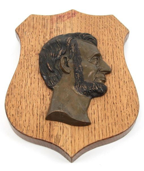 BRONZE ON WOOD SHIELD ABRAHAM LINCOLN PLAQUE: Bronze Profile of Abraham Lincoln, on wooden shield plaque. Marked on back "Harvey Larson / 788 Period / March 20, 1923". Good condition, with some wear to metal.