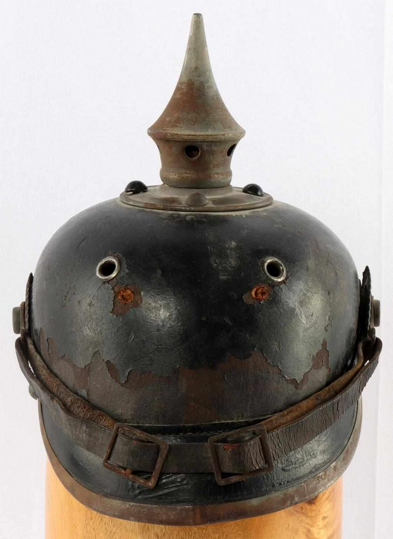 WWI PRUSSIAN PICKELHAUBE HARD LEATHER HELMET: WWI Prussian M1915 Pickelhaube. Hard black leather construction with grey metal trim and rivet to from brim and spike. Black leather chin strap intact with some cracking. Brown leather liner about 60%