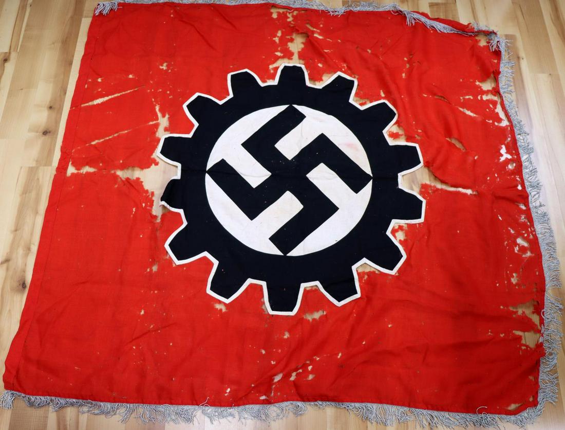 WWII GERMAN THIRD REICH DAF PARTY FLAG WITH FRINGE: WWII German Third Reich Deutsche Arbeitsfront Labor Party Flag. Flag is red cotton material, centered is a swastika encircled by a gear-wheel sewn to top, also cotton material. Has silver tasseled edg