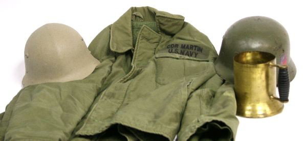 MILITARIA LOT HELMETS NAVY JACKET TRENCH ART: A Spanish Modelo helmet with repro Third Reich decals, a post war Soviet helmet , a trench art mug and a U.S. Navy deck jacket marked and named to Cdr. Martin.