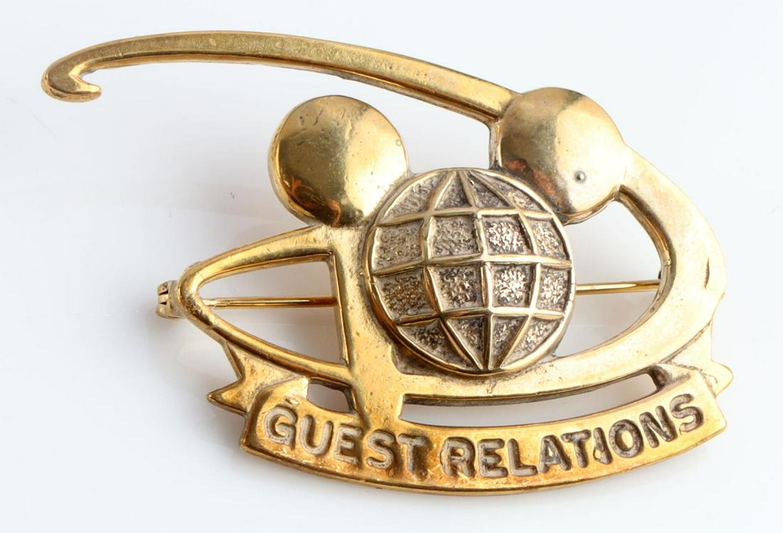 VINTAGE WALT DISNEY WORLD GUEST RELATIONS BADGE: Vintage Walt Disney World Cast Member GUEST RELATIONS Badge. Measures 2 X 1 3/8 inches. The front shows a Mickey Mouse likeness in the center of a D. The ribbon below reads GUEST RELATIONS. Has a thin