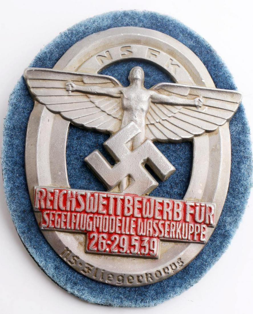 WWII GERMAN THIRD REICH NSFK 1939 KORPS BADGE: German WWII NSFK 1939 Glider Flieger Korps Badge. Measures 2 3/8” wide by 3” tall. The front shows the NSFK Icarus winged man with a swastika below in the center. It reads ‘NSFK Reichswettbewerb