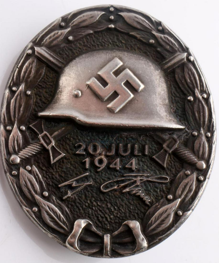 WWII GERMAN REICH 20 JULI 1944 HITLER WOUND BADGE: The presentation case measures 3 inches; wide by 3 1/4 inches tall by 1 3/16” deep. The reverse side is marked 800 2. Has a thin vertical pinback with a c catch. Die struck silver construction.