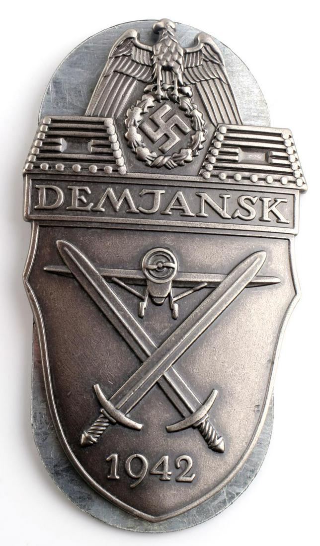 WWII GERMAN HEER DEMJANSK 1942 SLEEVE SHIELD: German WWII Army DEMJANSK 1942 Sleeve Shield. Measures 2 1/8 X 3 5/8 inches. The front shows an airplane in the center with a crossed pair of swords below. There is a Reichsadler at the top. It reads