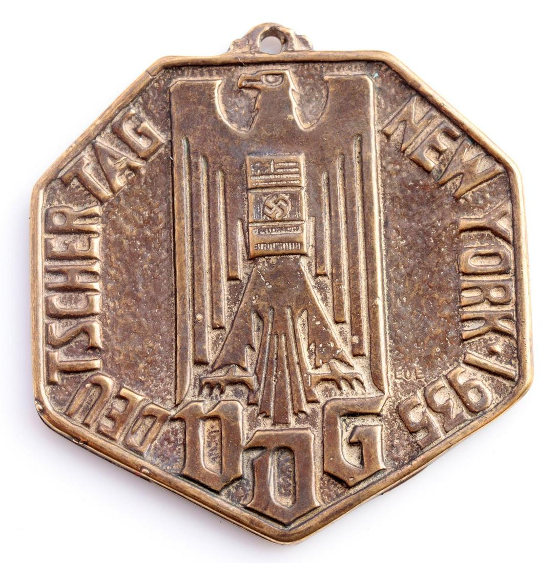 WWII GERMAN 1935 AMERICAN BUND DEUTSCHER TAG MEDAL: German American Bund WWII 1935 Deutscher Tag New York VDG Medal Decoration. Measures 1 5/16 X 1 9/16 inches. The front shows a Reichsadler. It reads ‘Deutscher Tag New York 1935 VDG’. The reverse 