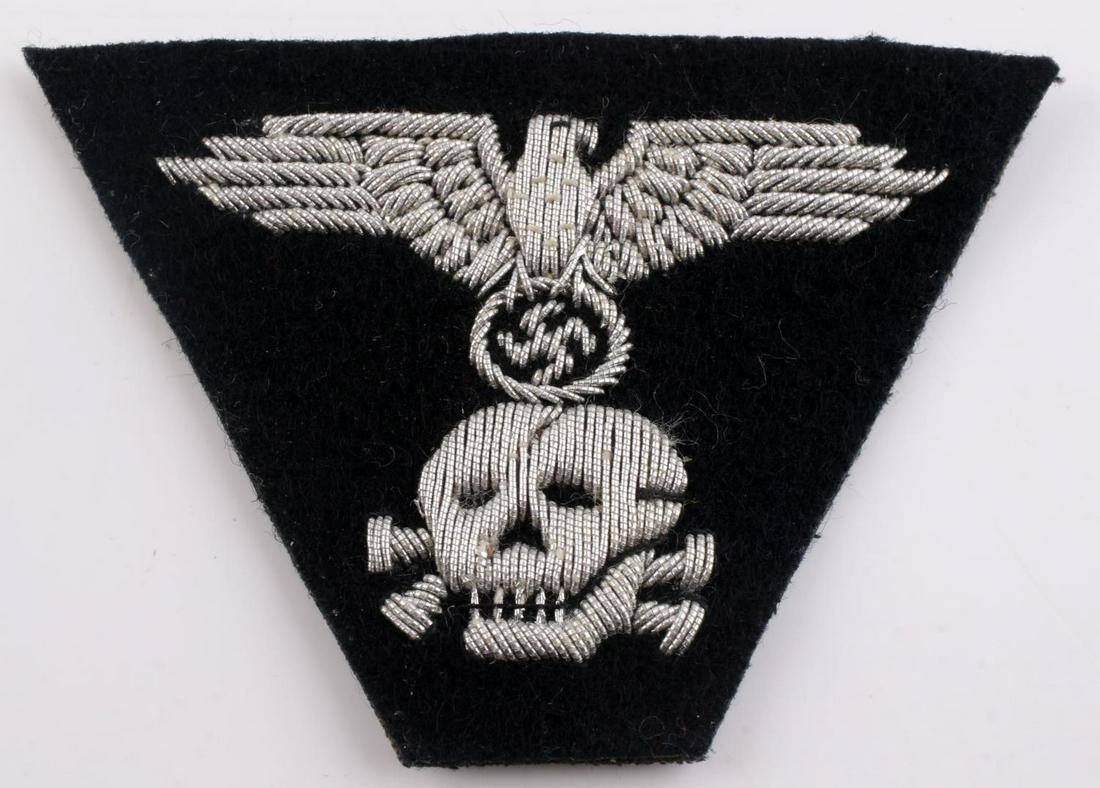 WWII GERMAN PANZER SS OFFICERS 4-43 CAP INSIGNIA: Measures 3” wide by 2 1/8” tall. The front shows a Waffen SS eagle clutching a swastika above with a Waffen SS skull and cross bones below. Has a ribbed cotton backing. Hand and machine em
