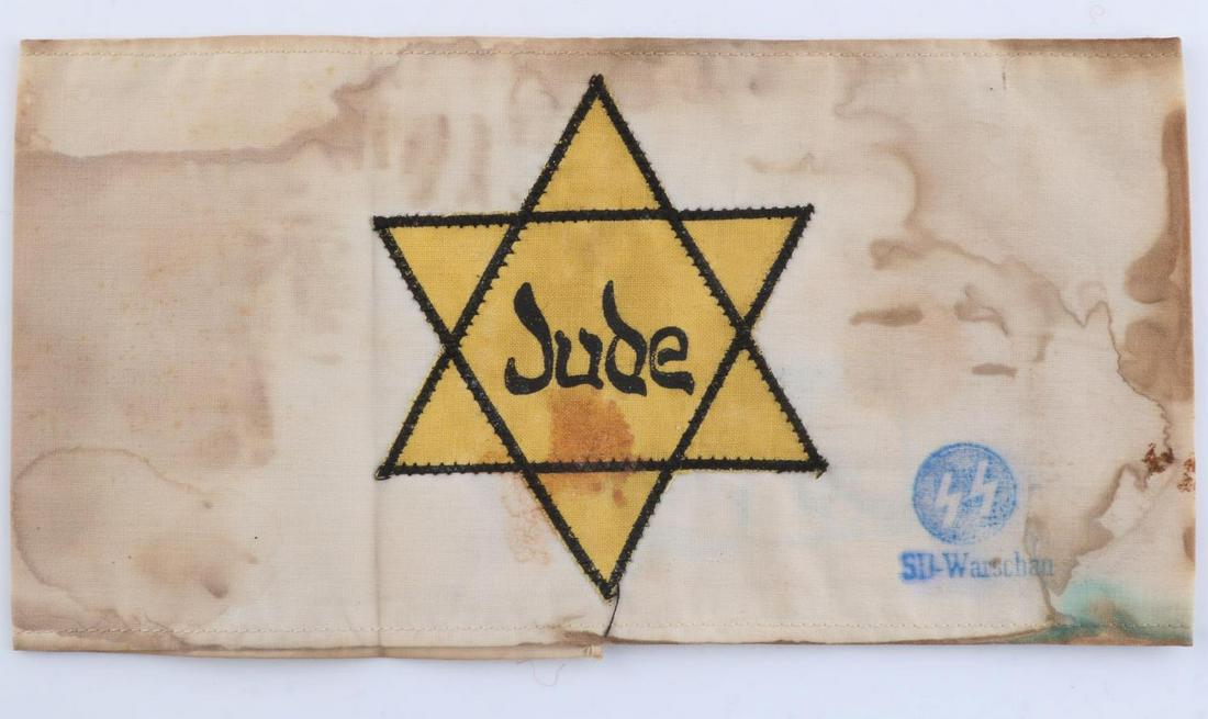WWII GERMAN THIRD REICH CONCENTRATION CAMP ARMBAND: German WWII Concentration Camp JUDE Arm Band. Measures 8” wide by 4 5/8” inches tall. The frontof the arm band reads ‘JUDE’ in the center of a Jewish Star. Has an SS runic stamp in the rightha