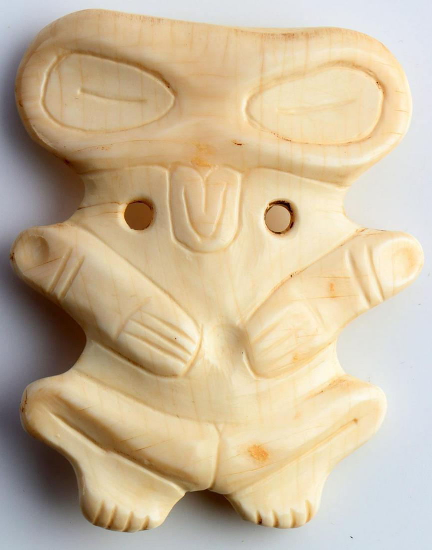 TAINO BIRD OWL MAN PENDANT OR ORNAMENT: Taino. Bird (owl) man pendant or ornament. The broad head is typical of owls. Human-like Arms rest on chest and legs bend outward the human-zoomorph representation indicates transition. Shell. Length 