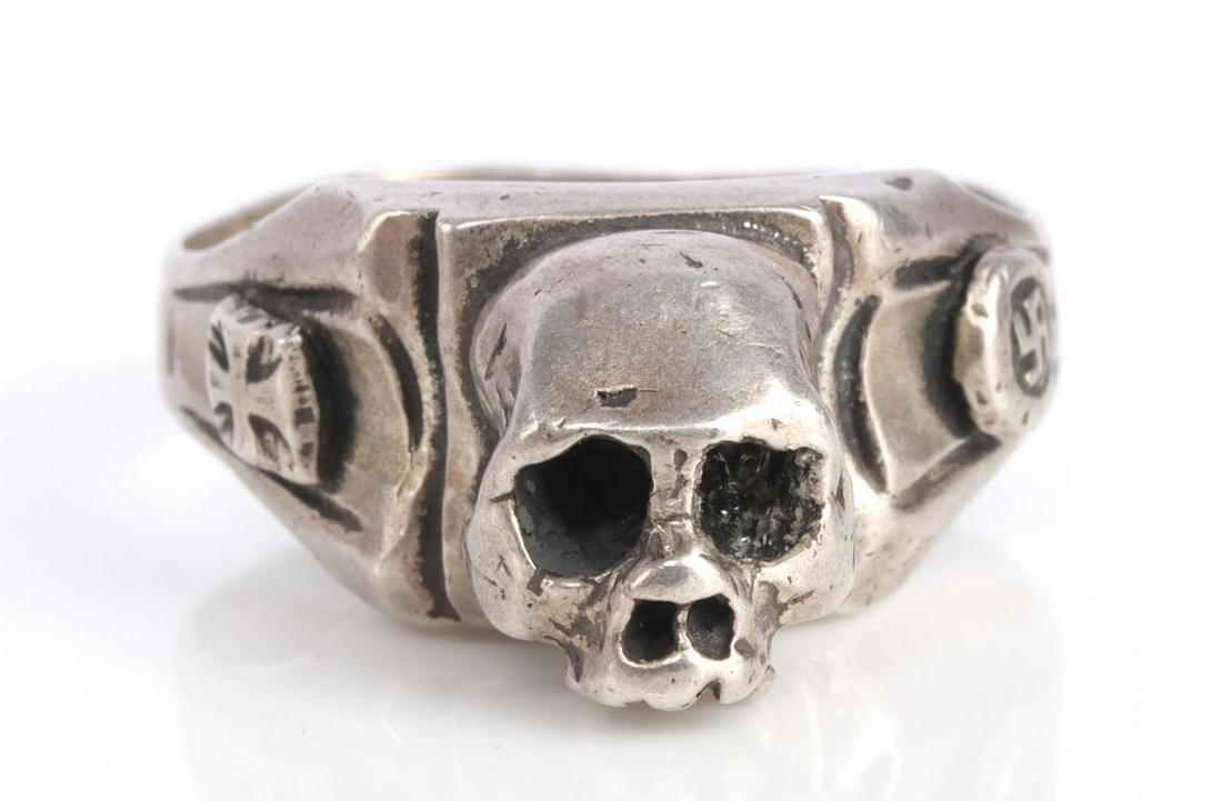 WWII GERMAN SILVER TOTENKOPF RING 14.5 SIZE: WWII German silver totenkopf ring. Likely made after the war. Size 14.5. Skull to center with Iron Cross to left and swastika to right. Marked 850. Tested for silver. This lot has a reserve.
