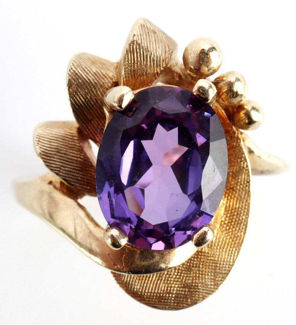 10KT GOLD WITH PURPLE SAPPHIRE MID CENTURY RING: Purple Sapphire measures 9.6 X 7.8mm (approx 2 1/2 carat) oval faceted cut with blue undertones along outer edge. Marked and tested 10kt yellow gold. Total weight of 4.8 grams. Size 6.25. This lot has
