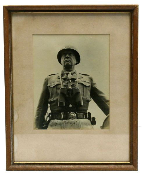 1943-44 AUTOGRAPHED PHOTO OF GEN. GEORGE S PATTON: A hand signed (below belt line) original photo of General George S. Patton Jr. standing in a tank hatch. This rare shot includes his famous pearl handled revolver, US belt buckle and tie instead of as