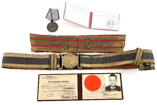GROUPING OF COLD WAR SOVIET ITEMS: Grouping of Cold War era Soviet items. Army belt, Soviet medal, KGB ID booklet, in original packaging, ID badge from US Embassy in Moscow, and a set of officers shoulder boards, showing significant mo