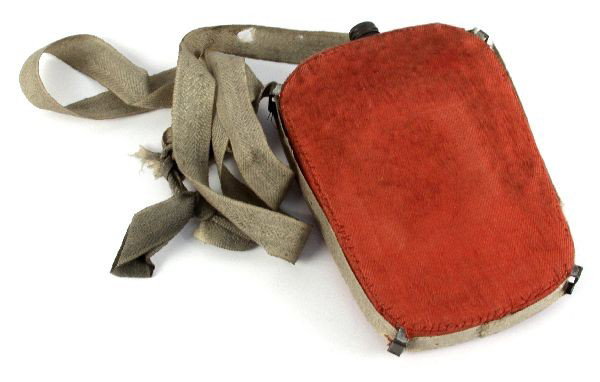 CIVIL WAR OR EARLIER RED LINEN COVERED CANTEEN: 8 by 5 inch canteen made of tin with a threaded cap, it is covered in a linen or cotton hand sewn cover with a white linen strap. Has been suggested piece may be a Zouave issue. Some minor mothing to 