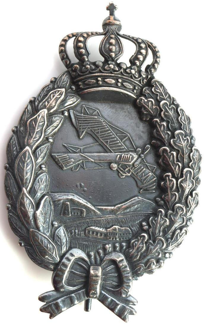WWI IMPERIAL GERMAN BAVARIAN PILOT BADGE: Imperial German World War I Aero Bavarian Aviator Pilot Badge. Measures 1 3/4 wide by 2 3/4 inches tall. The front shows an airplane flying over some buildings and small mountains in the center. They 