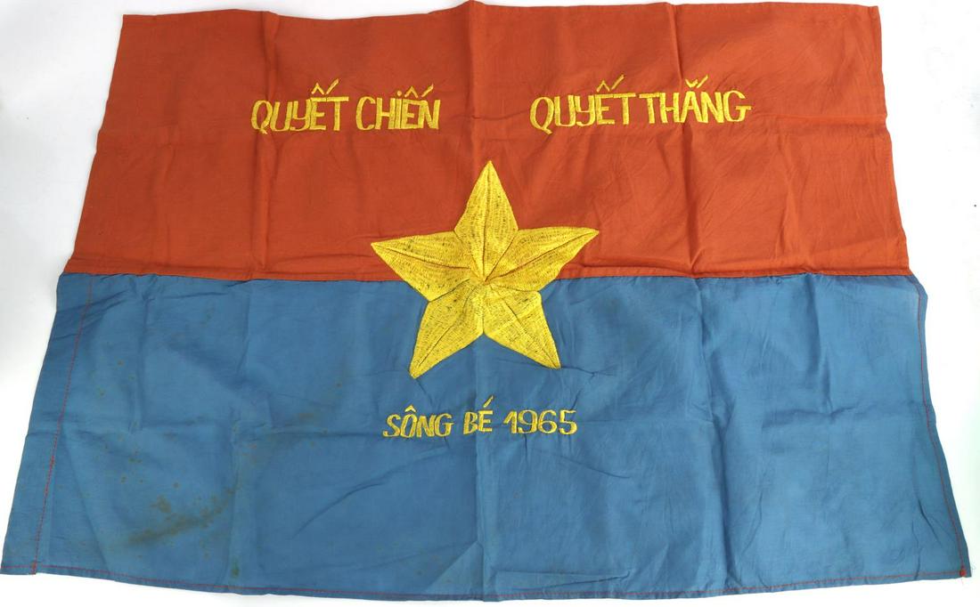 VIETNAM CIVIL WAR VIET CONG 1965 BANNER FLAG: Measures 29 5/8 inches wideby 21 inches tall. The front reads ‘QUYET CHIEN QUYET THANGSONG BE’. It is also dated ‘1965’. Shows a yellow star in the center surrounded by an oak leaf wreath. Two