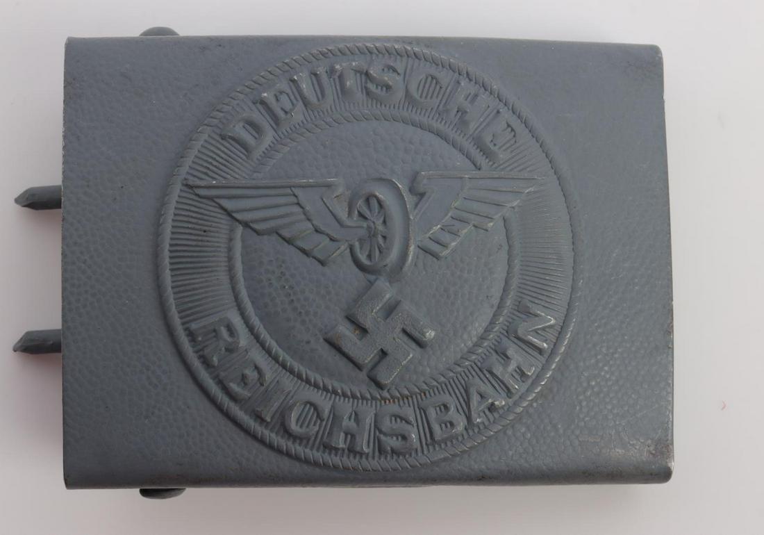 WWII GERMAN REICHSBAHN EM BELT BUCKLE: German WWII Reichsbahn Railway EM Belt Buckle. Measures 2 1/2 X 1 7/8 inches. Front shows a wheel in the center flanked by a wing on each side a swastika below. Reads ‘Deutsche Reichsbahn’. Includ