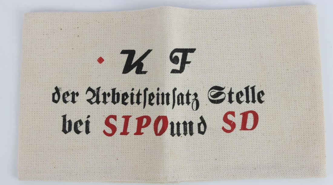 WWII GERMAN REICH SICHERHEITSPOLIZEI ARMBAND: Measures 8 1/2 inches wide by 4 3/4 inchestall. The front reads ‘K F der Urbeitseinsatz Stelle bei SIPO und SD’. One piece machine sewnprinted white cotton linen construction. Unauthenticated, sol