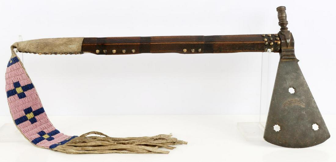 PLAINS INDIAN TOMAHAWK PEACE PIPE W BEADED DROP: Native American Peace Pipe Tomahawk circa 19th century with brain tanned buckskin beaded drop and brass tack adornments. Length of stem and head is 2 feet, blade and pipe are 13 inches, and beaded dro