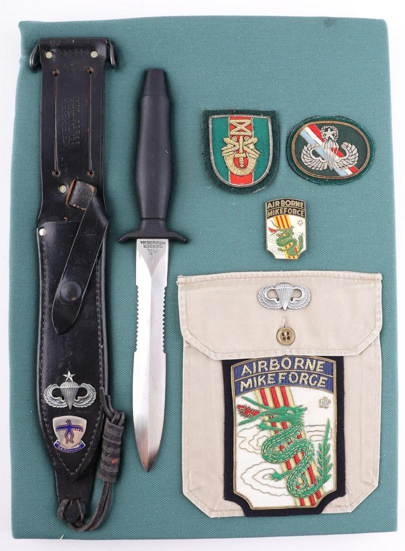VIETNAM AIRBORNE MIKE FORCE FIGHTING KNIFE & PATCH: Display box measuring 16 x 12 inches, contains 11 1/2 overall Gerber knife with sheath with jump master wings and airborne DUI, additional beret flash, and in country patches.