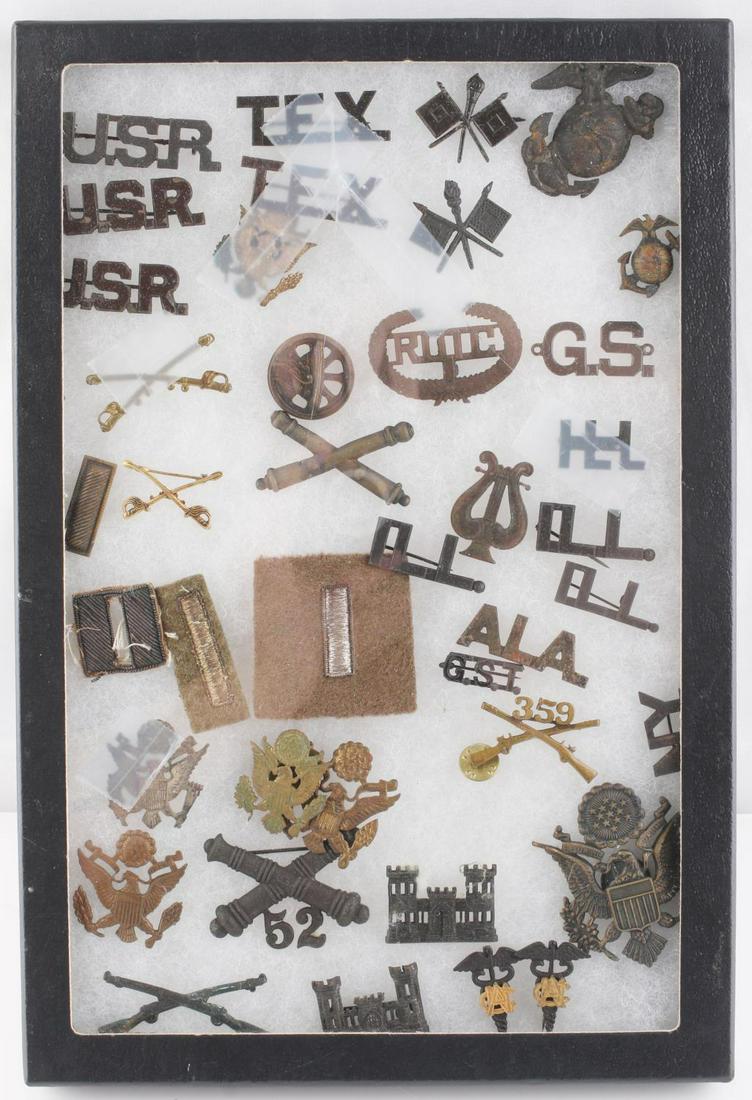 M1902 SPAN AM WWI US ARMY RESERVE INSIGNIA LOT: Good selection of state titles, Artillery cap and collar badges, Infantry, two USMC EGA's that appear dug. In a Riker mount with broken glass.