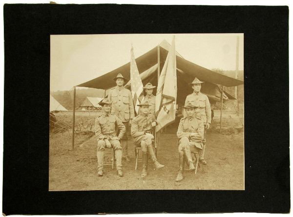 ANTIQUE SPAN AM WAR PHOTO OF 6 SOLDIERS ID: Antique 1906 Spanish American war photo of six soldiers at camp holding flags. Photo measures 9.75 by 7.75 inches. Overall in good condition with soldiers identified on back. One soldier identified as
