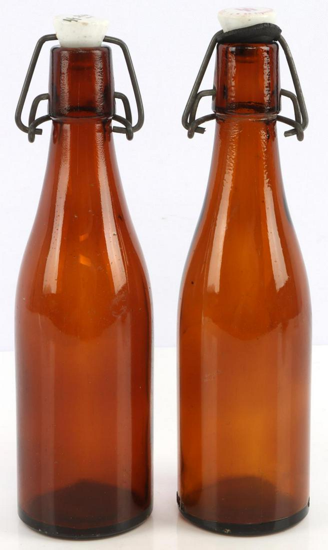 2 WWII GERMAN REICH SS EIGENTUM & SS-REICH BOTTLES: Lot of 2 WWII German Reich beer bottles including an SS Eigentum beer bottle with "Tr. Ub. Pl. Heidelager" markings on the cap. An SS-Reich beer bottle dated 1940 on the cap. Good condition. Unauthent