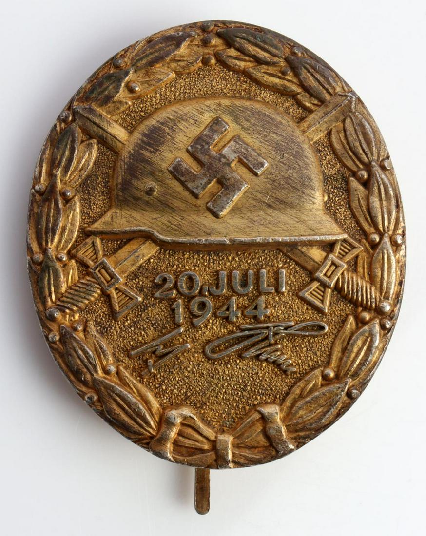 WWII GERMAN GOLD 20 JULI 1944 HITLER WOUND BADGE: WWII German Gold Adolf Hitler Wound badge. Obverse features helmet with swastika with crossed sword behind above "20 Juli 1944" with a facsimile Hitler signature. Pebbled background with an oak leaf w