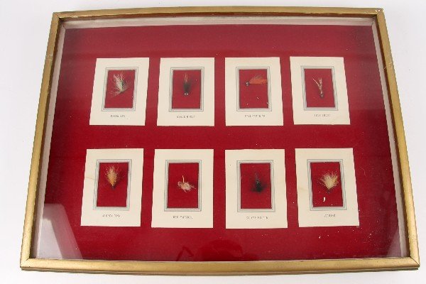 EIGHT FISHING FLIES IN FRAMED SHADOW BOX: Eight fishing flies framed in shadow box. Labeled "Green Bug", "Black Ghost", "Fall Favorite", "Grey Ghost", "Mickey Finn", "Red Maribou", "Silver Hilton", and "Herring". One fly has been dislocated f