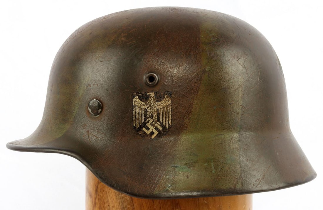 WWII GERMAN REICH HEER M40 CAMO DECAL HELMET: Camouflage finish on exterior still present with some wear. 9-fingered leather liner intact. Heat stamp on rear of helmet marked "10029" on side of helmet marked "SE64". Heer decal on left side of hel