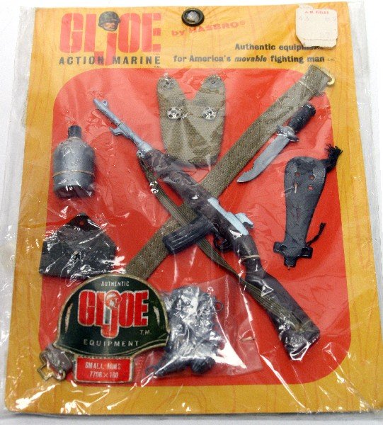 1964 HASBRO G I JOE EQUIPTMENT IN ORIGINAL PACKAGE: G.I. Joe "action Marine" equipment model number 7706X160. In original packaging including MM77-00 Marine Manual dated 1964 in package. Peg hook card has J.M. Fields sticker with original price of ".87